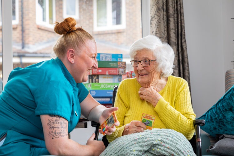 resident playing cards with carer