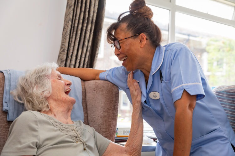 resident sitting down laughing with carer
